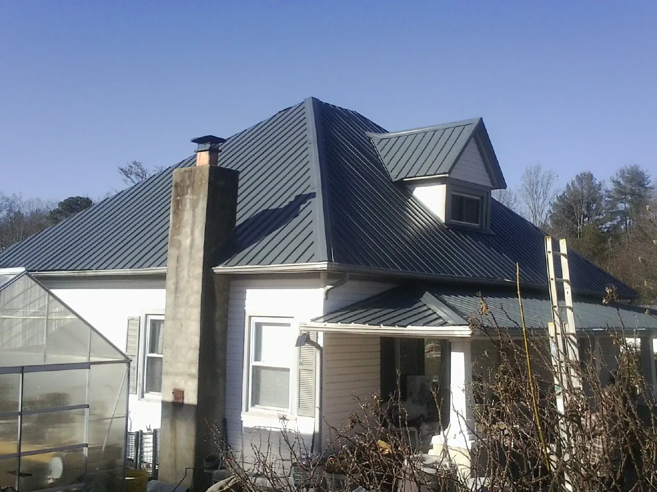 Dark blue standing seam metal roof on a white farmhouse with dormer — Slate & Tile Roof Repair by Roofing Brothers in Victory Mills