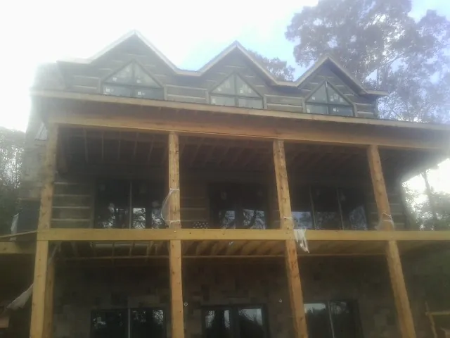 Dormers and porch framing on a large log home under construction — Roof Coating work by our crew in Victory Mills