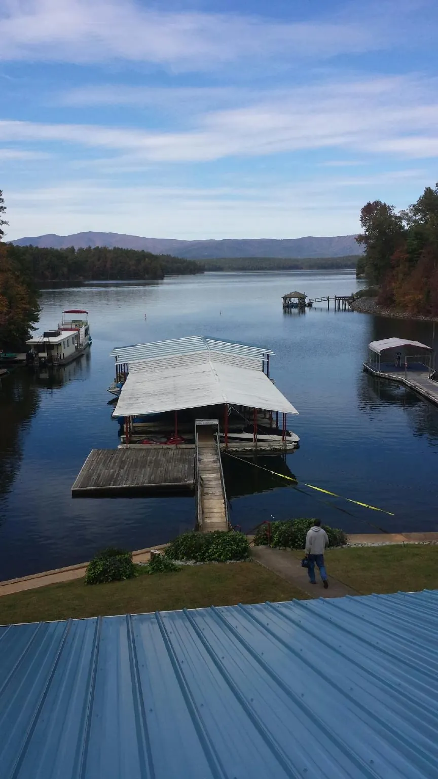 View across a lake from a newly installed blue metal roof in Victory Mills