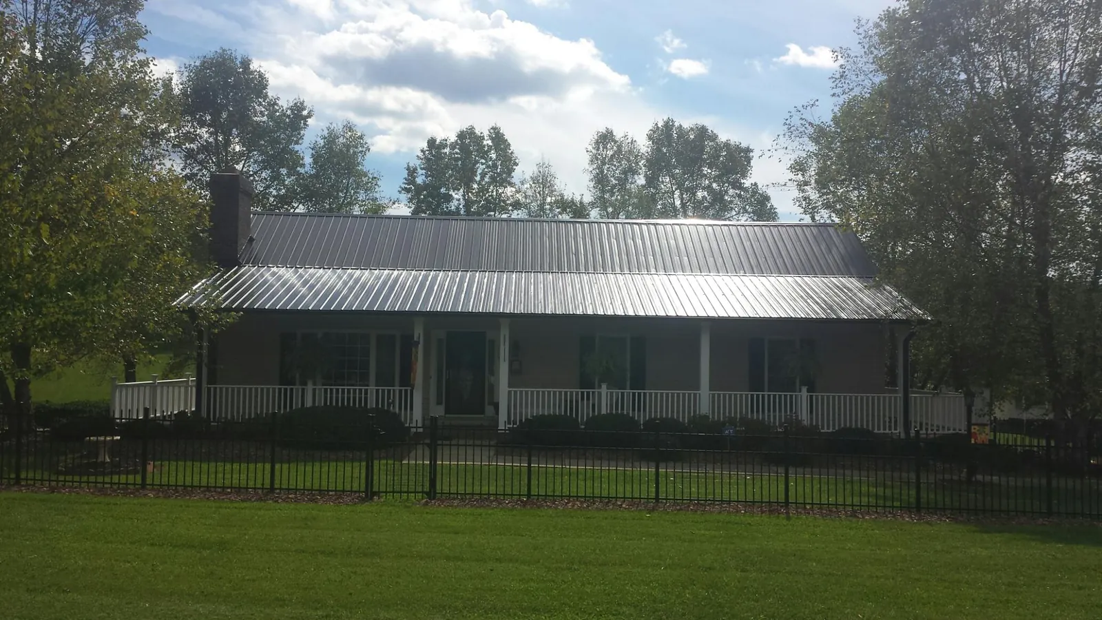 Gray metal roof on a brick ranch with a full width front porch — Gutter Guard Installation work by our crew in Victory Mills