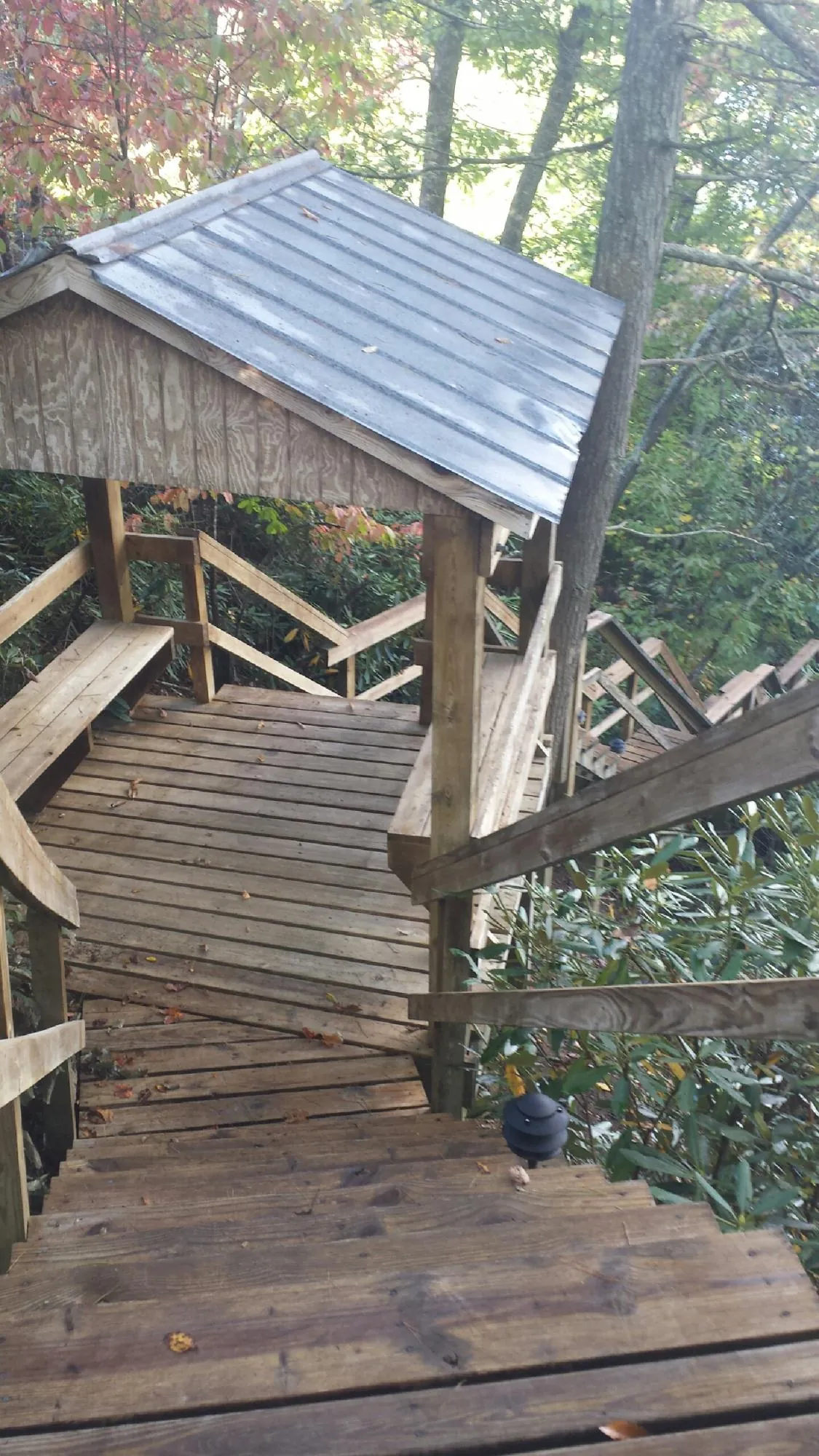 Metal roofed shelter over wooden steps on a wooded walkway — Skylight Repair & Installation work by our crew in Victory Mills