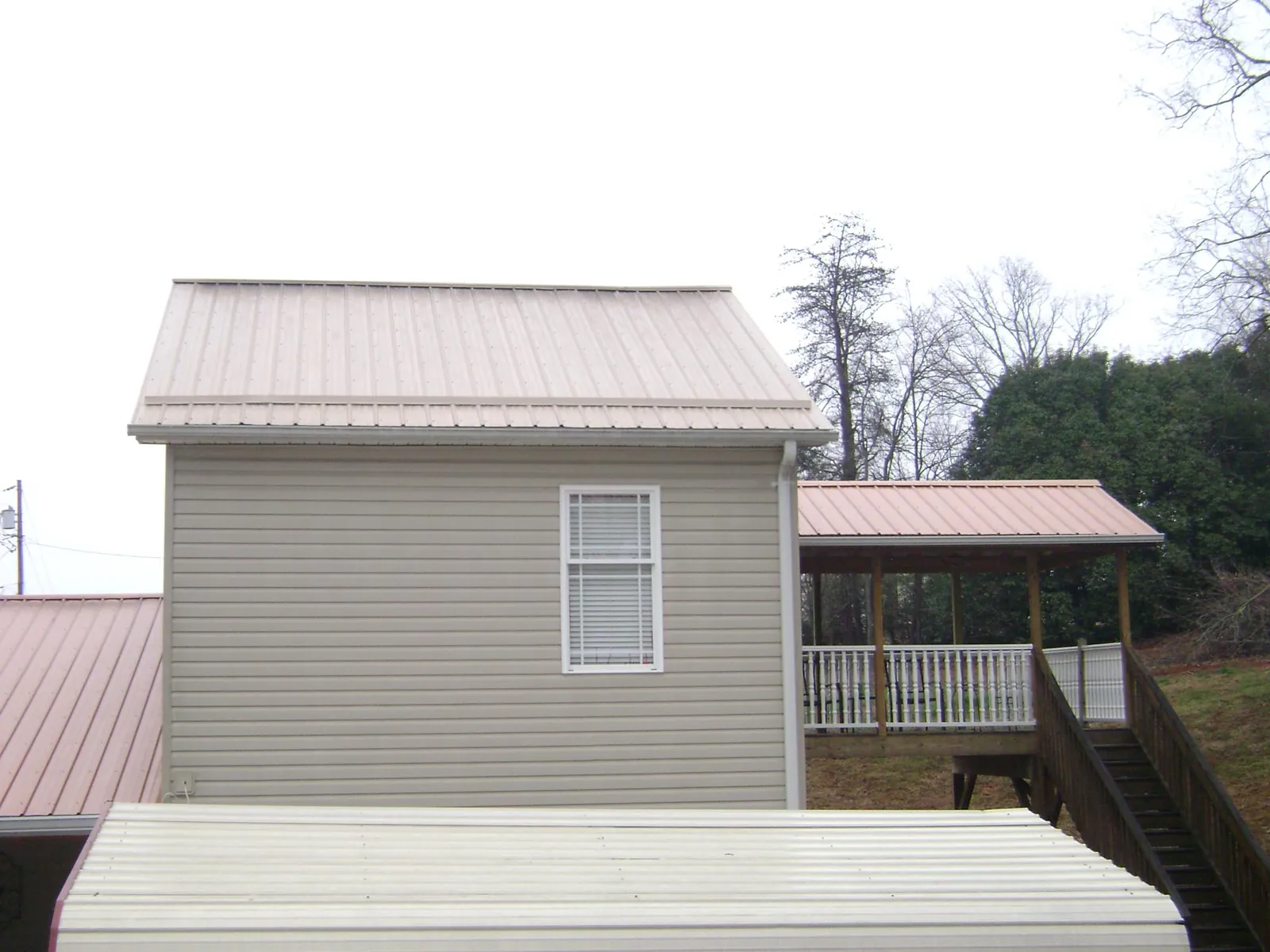 Tan metal roofs on a two story addition and attached porch, from a Roof Replacement job in Victory Mills