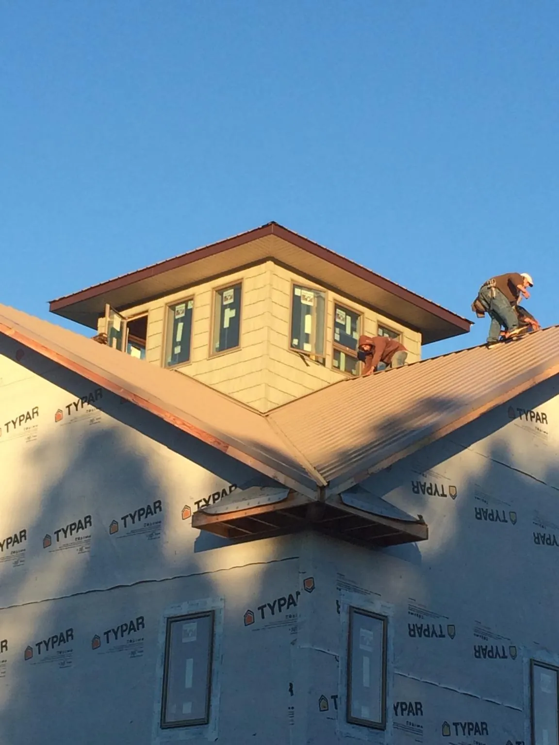 Roofers working around a rooftop cupola on a new metal roof at sunset — Roof Waterproofing in Victory Mills by Roofing Brothers